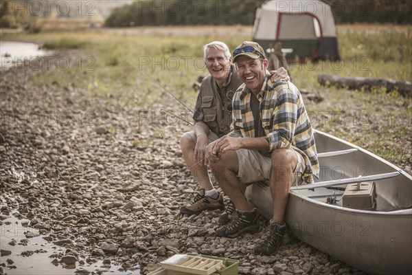 Caucasian father and son sitting in canoe at campsite