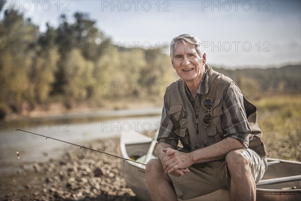 Older Caucasian man holding fishing rod near river