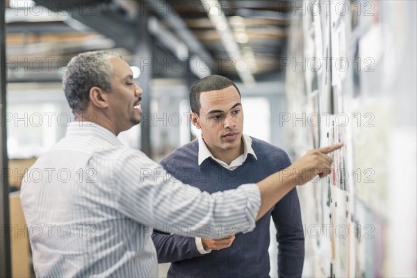 Businessmen examining photographs on wall in office