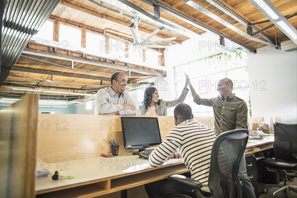 Business people celebrating at desk in office