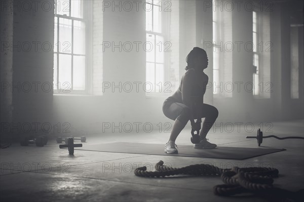 Black woman lifting weights in dark gym