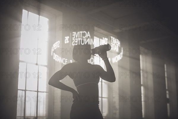 Virtual words circling Black athlete drinking from bottle