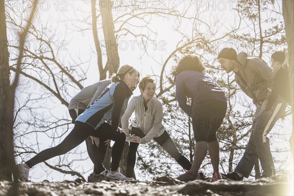 Low angle view of athletes stretching in forest