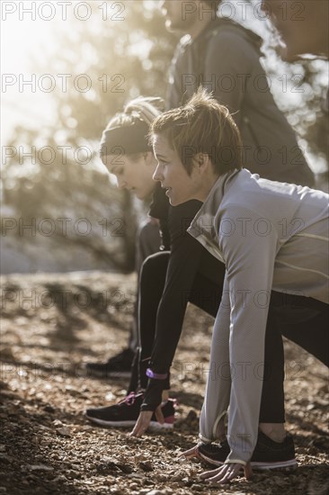 Runners stretching on dirt ground