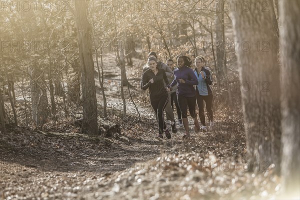 Runners jogging on dirt path in forest