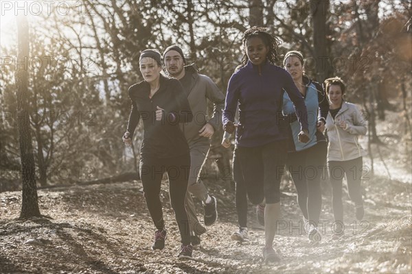 Runners jogging on dirt path in forest