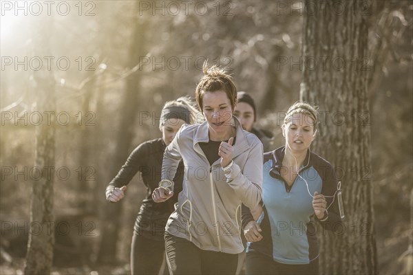 Runners jogging on dirt path in forest