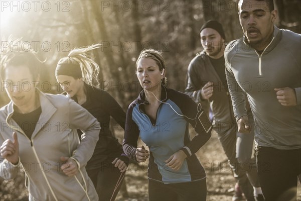 Runners jogging on dirt path in forest