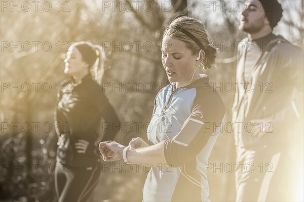 Caucasian runner checking fitness watch in forest