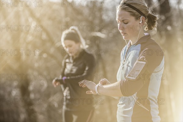 Caucasian runners checking fitness watches in forest