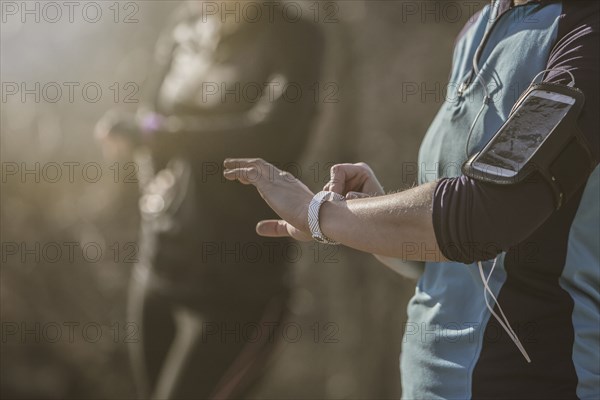 Caucasian runners checking fitness watches in forest