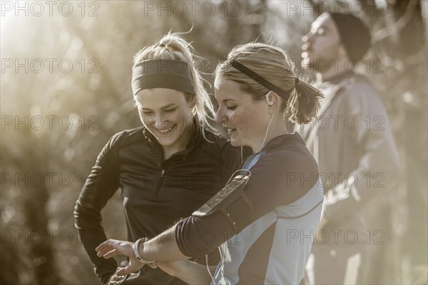 Caucasian runners checking fitness watch in forest