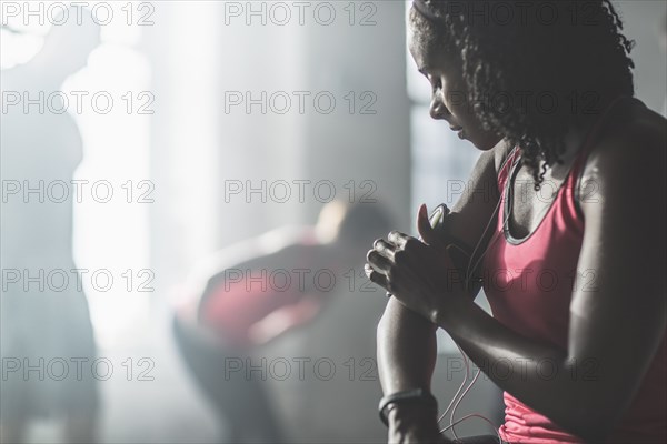Athlete adjusting mp3 player armband in gym