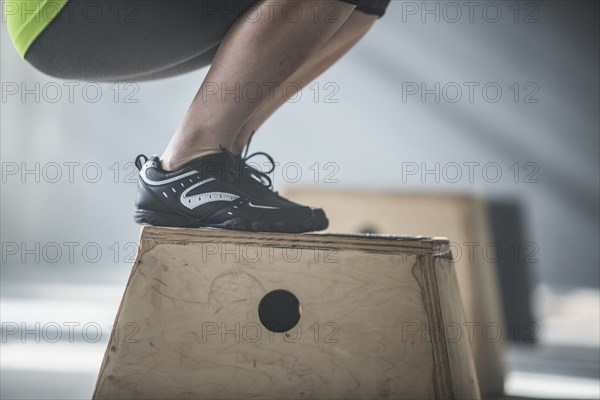 Athlete crouching on platform in gym