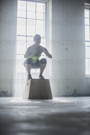 Athlete crouching on platform in gym