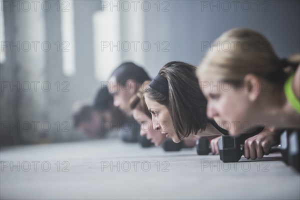 Athletes doing push-ups and lifting weights on floor