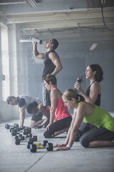 Athletes drinking water bottles near dumbbells