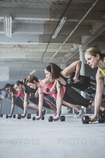 Athletes doing push-ups with dumbbells on floor