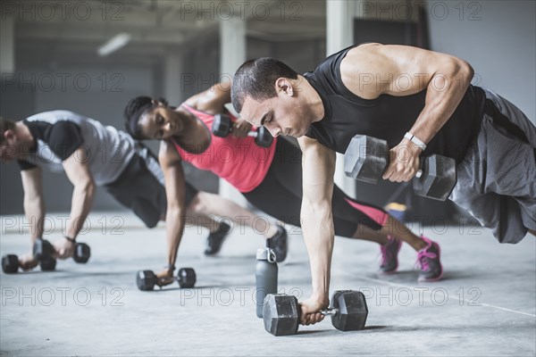 Athletes doing push-ups with dumbbells on floor