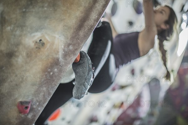 Close up of athlete climbing rock wall in gym