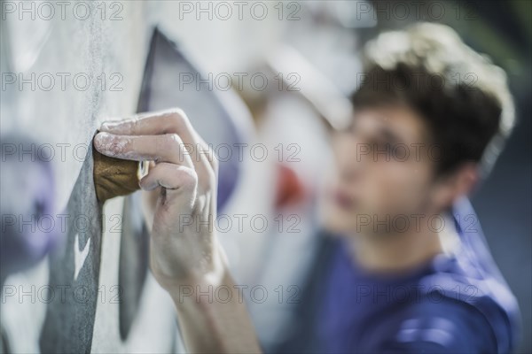 Close up of athlete climbing rock wall in gym