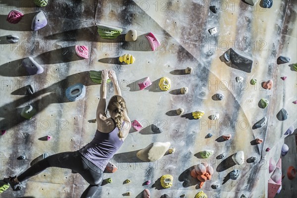 Athlete climbing rock wall in gym