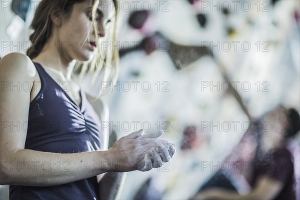 Athlete chalking her hands at rock wall in gym