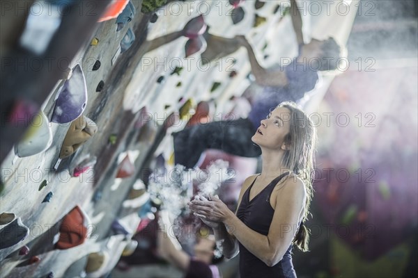 Athlete chalking her hands at rock wall in gym