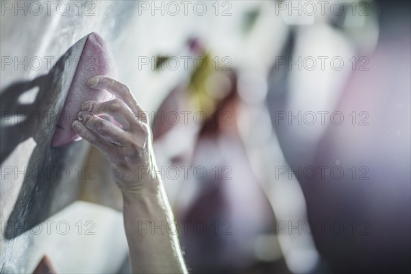 Close up of athlete climbing rock wall in gym