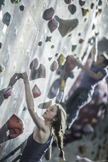 Athletes climbing rock wall in gym