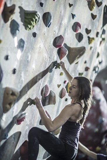 Athlete climbing rock wall in gym