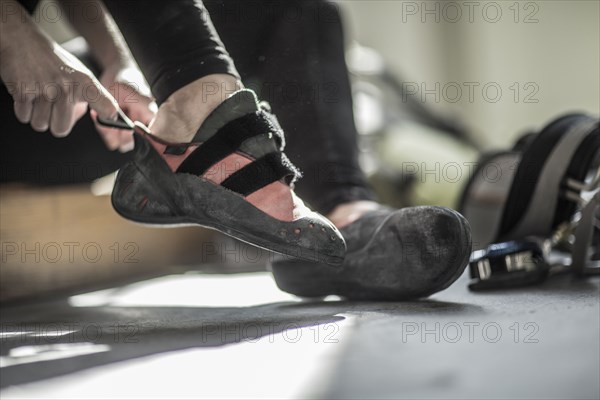 Athlete pulling on climbing shoes in gym