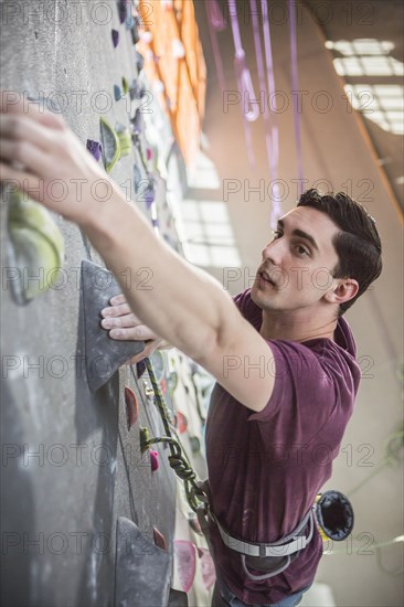 High angle view of athlete climbing rock wall in gym