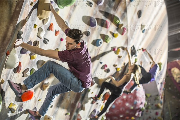 Athletes climbing rock wall in gym