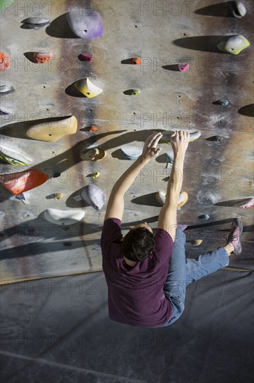 High angle view of athlete climbing rock wall in gym