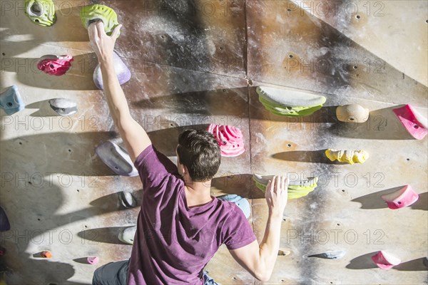 High angle view of athlete climbing rock wall in gym