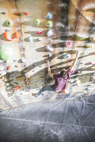 High angle view of athlete climbing rock wall in gym