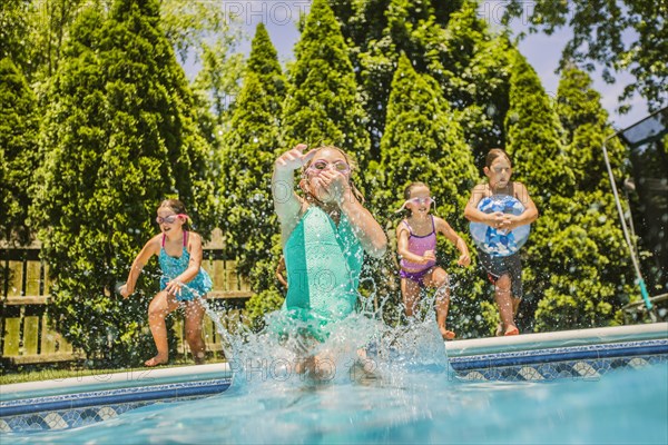 Caucasian girls jumping into swimming pool