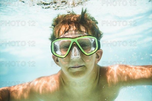 Caucasian boy swimming underwater in swimming pool