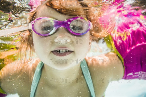 Caucasian girl swimming underwater in swimming pool