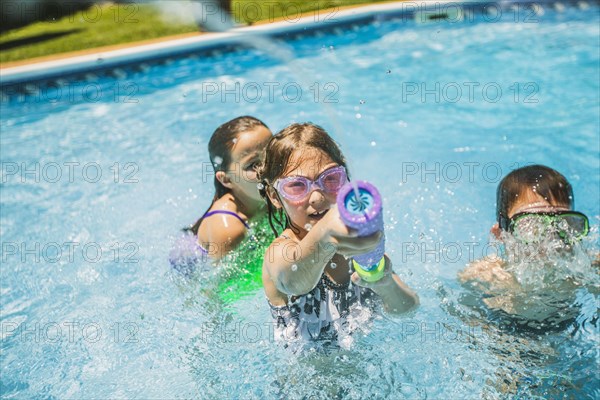 Children playing with squirt gun in swimming pool