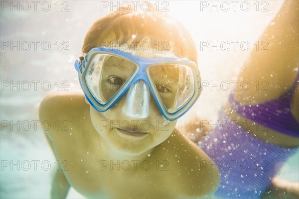 Caucasian boy swimming underwater in swimming pool