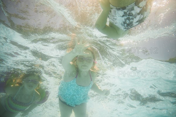 Caucasian children swimming underwater in swimming pool