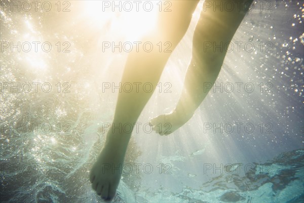 Caucasian girl swimming underwater in swimming pool