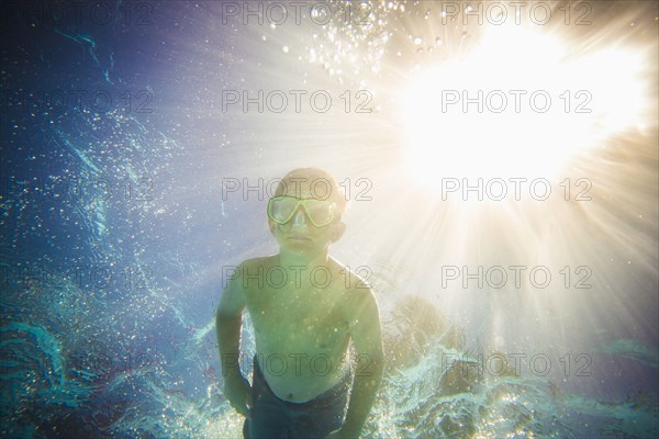 Caucasian boy swimming underwater in swimming pool