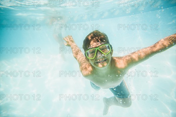 Caucasian boy swimming underwater in swimming pool