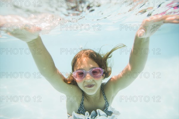Caucasian girl swimming underwater in swimming pool