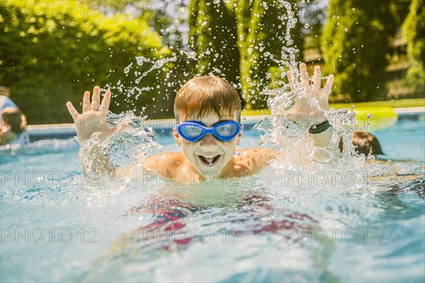 Boy splashing in swimming pool