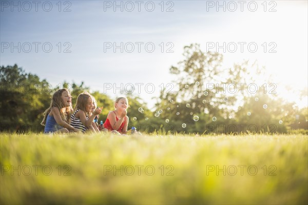 Girls blowing bubbles in grass field