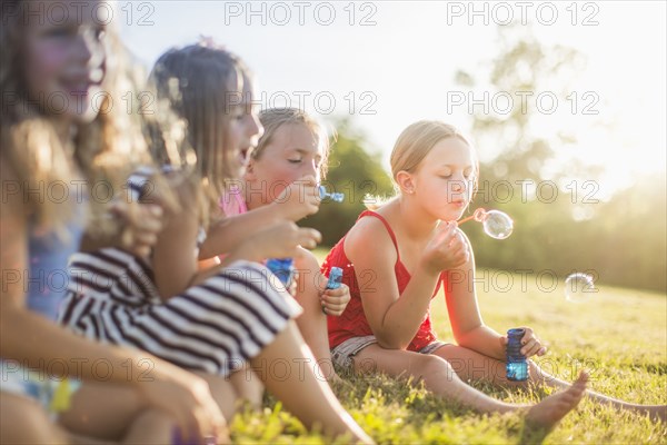 Girls blowing bubbles in grass field